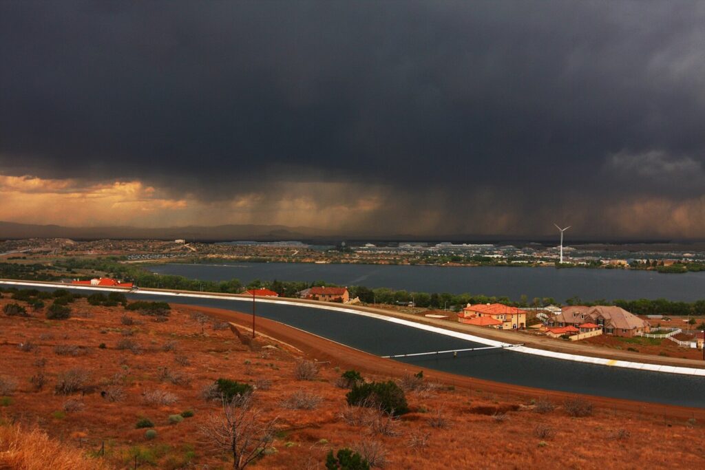 Dark storm clouds over Lake Palmdale and the aqueduct with red desert brush in the foreground, Palmdale, CA, The Lavatory Los Angeles