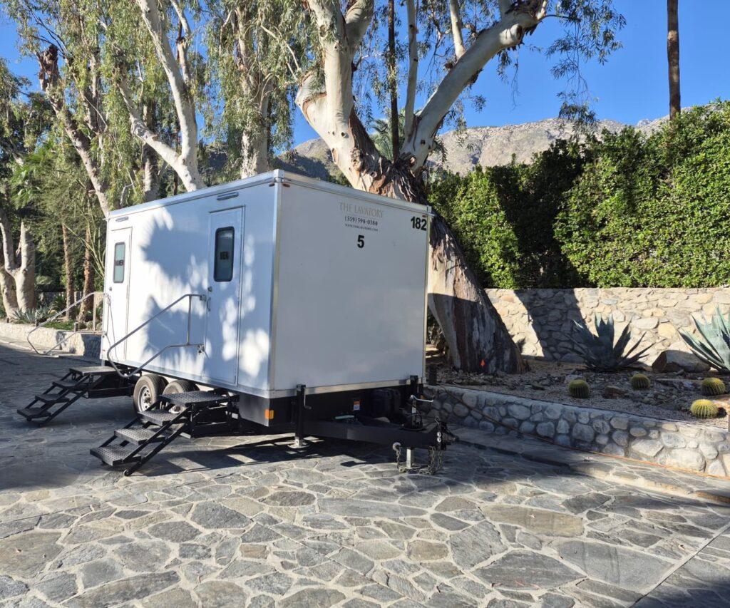 5-station bathroom trailer on a flagstone drive under eucalyptus trees with mountains behind it, The Lavatory Los Angeles