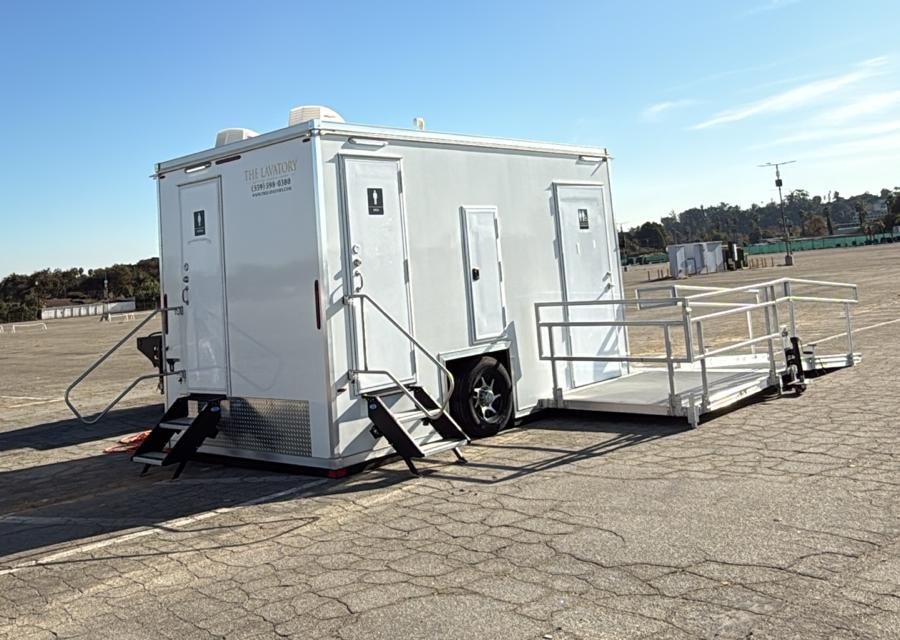 ADA plus 2 bathroom trailer with a railed ramp platform on a large paved lot in Pomona, The Lavatory Los Angeles