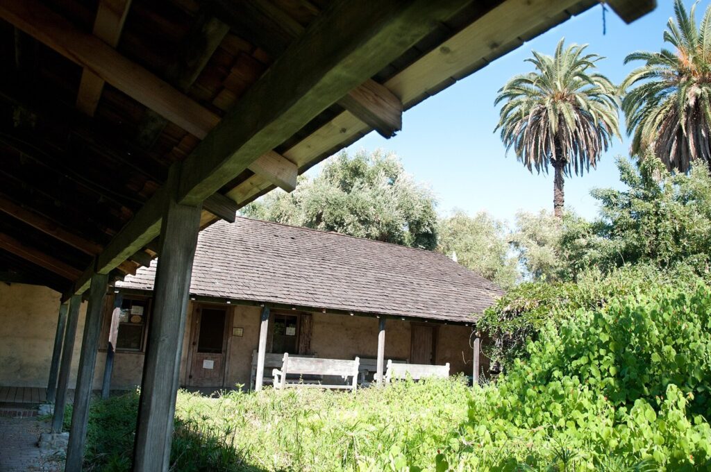 Covered porch, wood benches and palm trees at the Ygnacio Palomares Adobe on Arrow Highway in Pomona, CA, The Lavatory Los Angeles