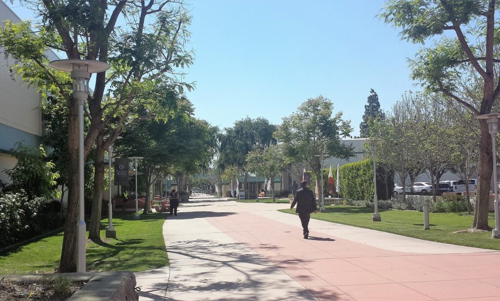 Tree-lined campus walkway with people walking at Western University of Health Sciences in Pomona, CA, The Lavatory Los Angeles