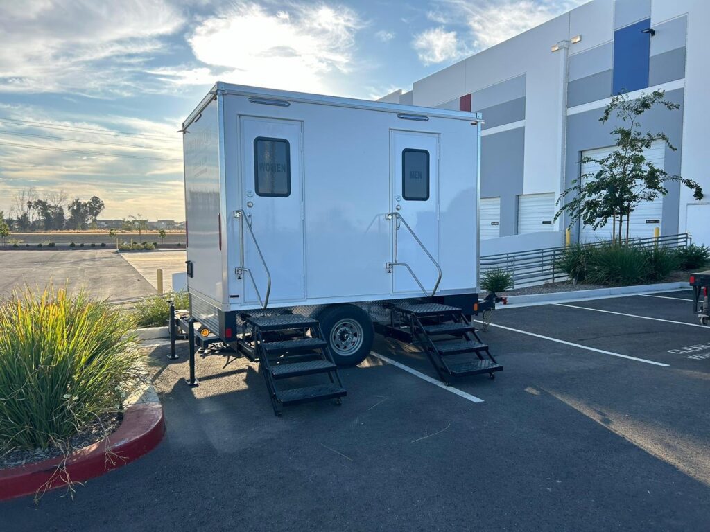 2-station bathroom trailer with women's and men's doors in a business park parking lot at sunrise, The Lavatory Los Angeles