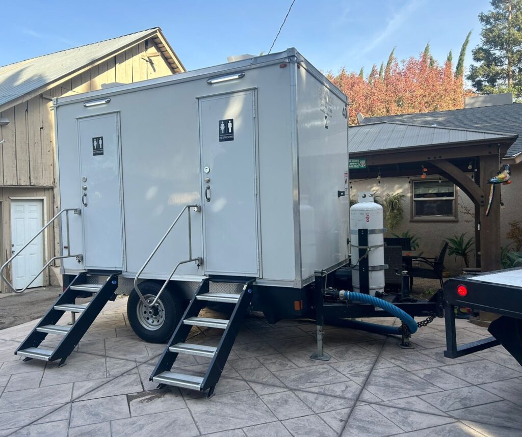 2-station bathroom trailer with steps and a fresh water hookup on a stamped concrete patio at a home, The Lavatory Los Angeles