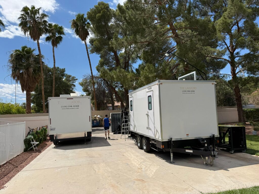 Two bathroom trailers on a long driveway under palm trees while our crew sets up for a home party, The Lavatory Los Angeles