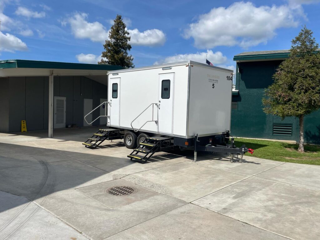 5-station bathroom trailer parked on a school walkway between classroom buildings, The Lavatory Los Angeles