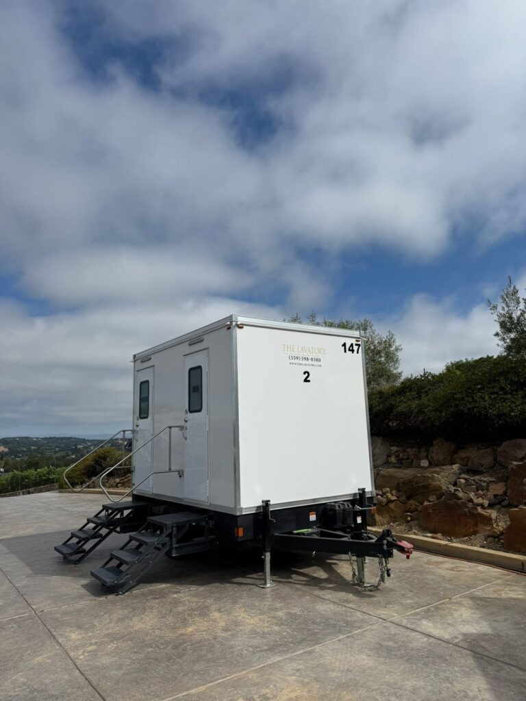 2-station bathroom trailer set on a hilltop patio with a view of the hills under a cloudy sky, The Lavatory Los Angeles