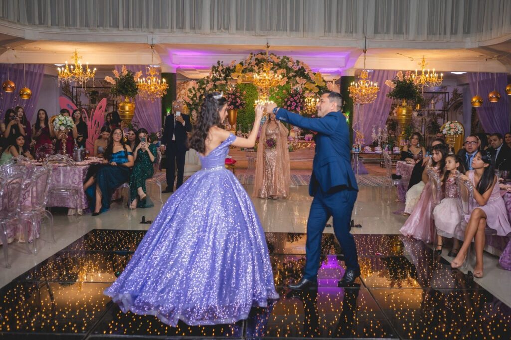 Quinceanera in a sparkling lavender gown dancing with her father as guests watch in a decorated ballroom, The Lavatory Los Angeles