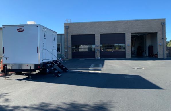 Shower trailer parked outside a fire station with its apparatus bay doors, The Lavatory Los Angeles