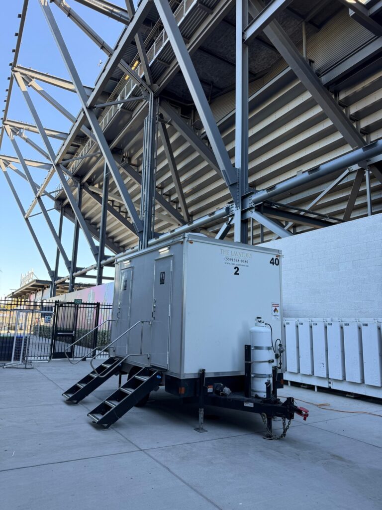 2-station combo trailer parked under the steel grandstand of a soccer stadium, The Lavatory Los Angeles
