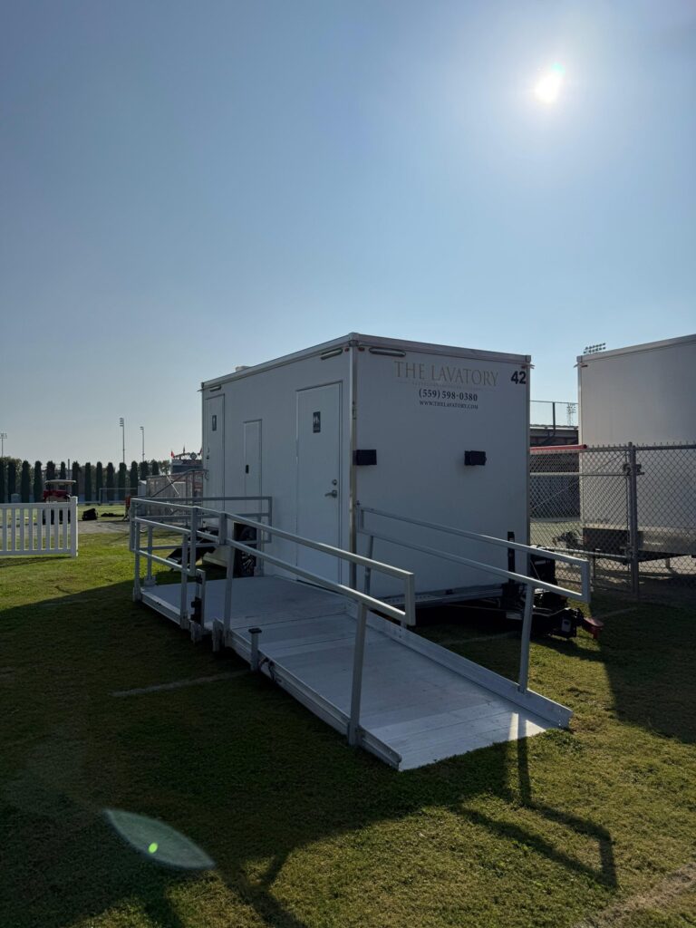 Accessible bathroom trailer with a long ramp on the lawn outside a stadium on game day, The Lavatory Los Angeles