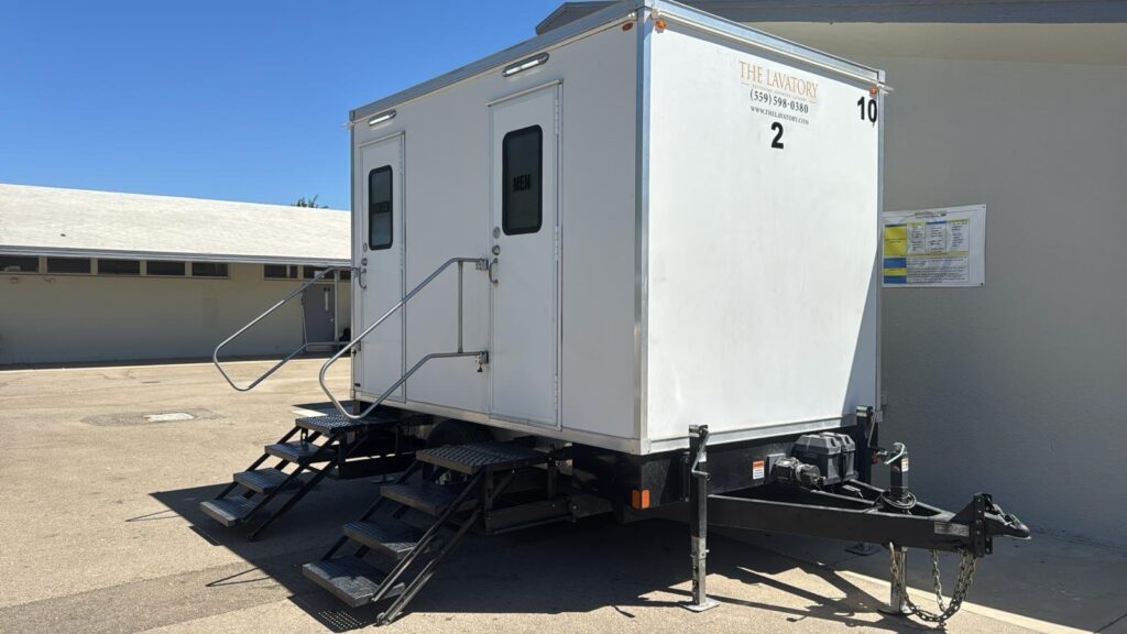 2-station bathroom trailer parked against a school building wall, The Lavatory Los Angeles