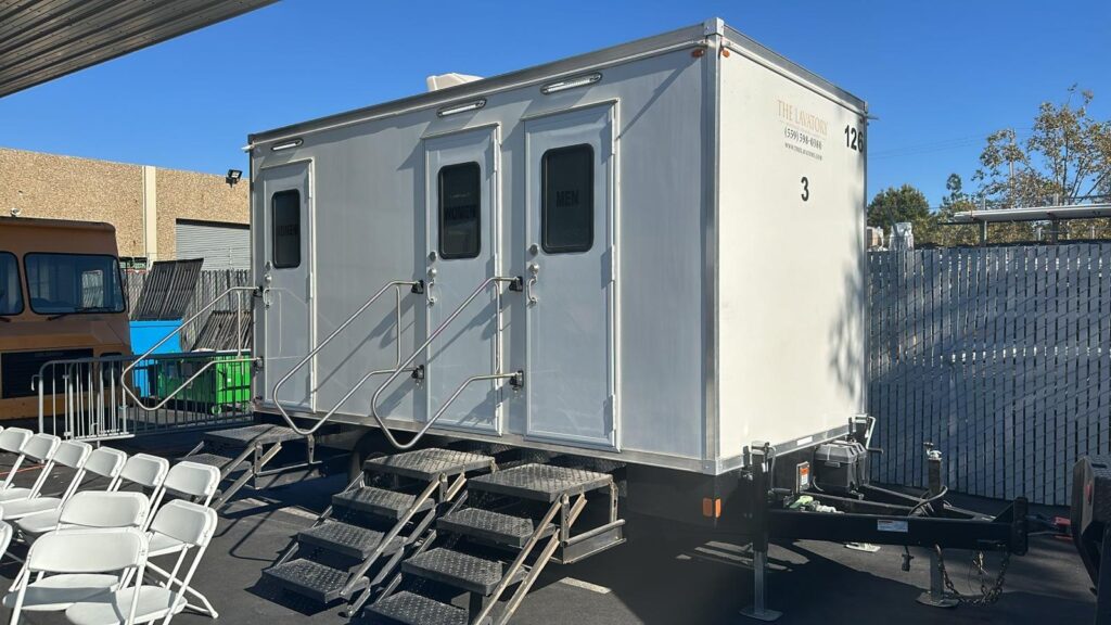 3-station bathroom trailer next to rows of white folding chairs, The Lavatory Los Angeles