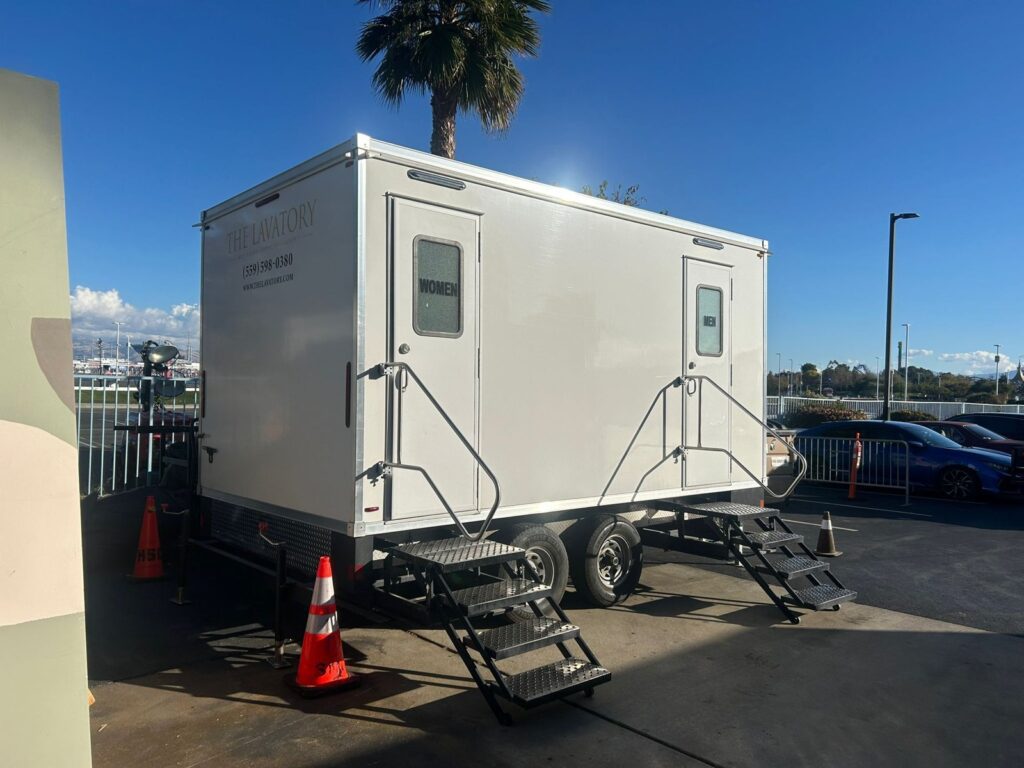 5-station bathroom trailer with women's and men's doors in a palm-lined lot, The Lavatory Los Angeles