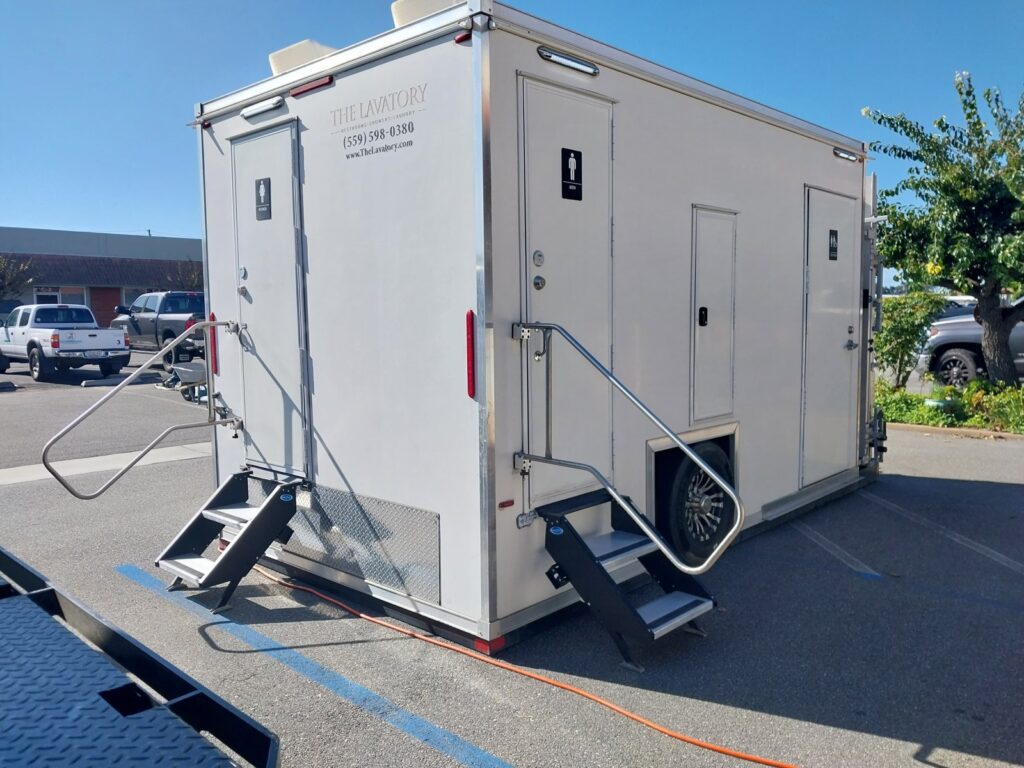Bathroom trailer with a men's door, steps and handrails in an office parking lot, The Lavatory Los Angeles
