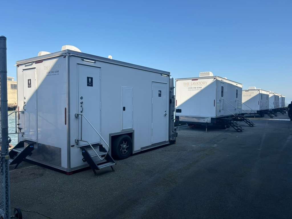 Several luxury bathroom trailers lined up in a row on a paved yard, The Lavatory Los Angeles